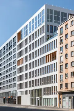 This 8-storey office building was completed in 2021, part of a major redevelopment project in the Vache-Noire district. This mixed structure of wood and concrete is finished with a white glass 5x5cm mosaic on the ventilated facade, evoking the Pate de Verre used on buildings in the area during the 1980s.