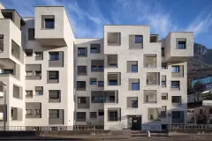 View of buildings on Via Aslago, showing the new top floor vertical extension, and the new facade's recessed window surround details in contrasting grey render finishes