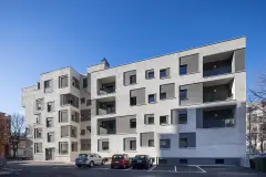 View of the side of the buildings on Via Aslago, Bolzano, Italy, showing the new facade's window details in contrasting grey render finishes, and new balconies and loggias. Photo: Andrea Zanchi