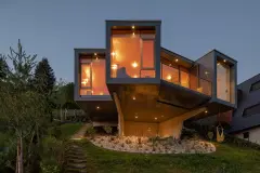 Night view of Villa Mimi at Lake Millstatt cantilevers over a hillside, finished with blue glass mosaic tiles